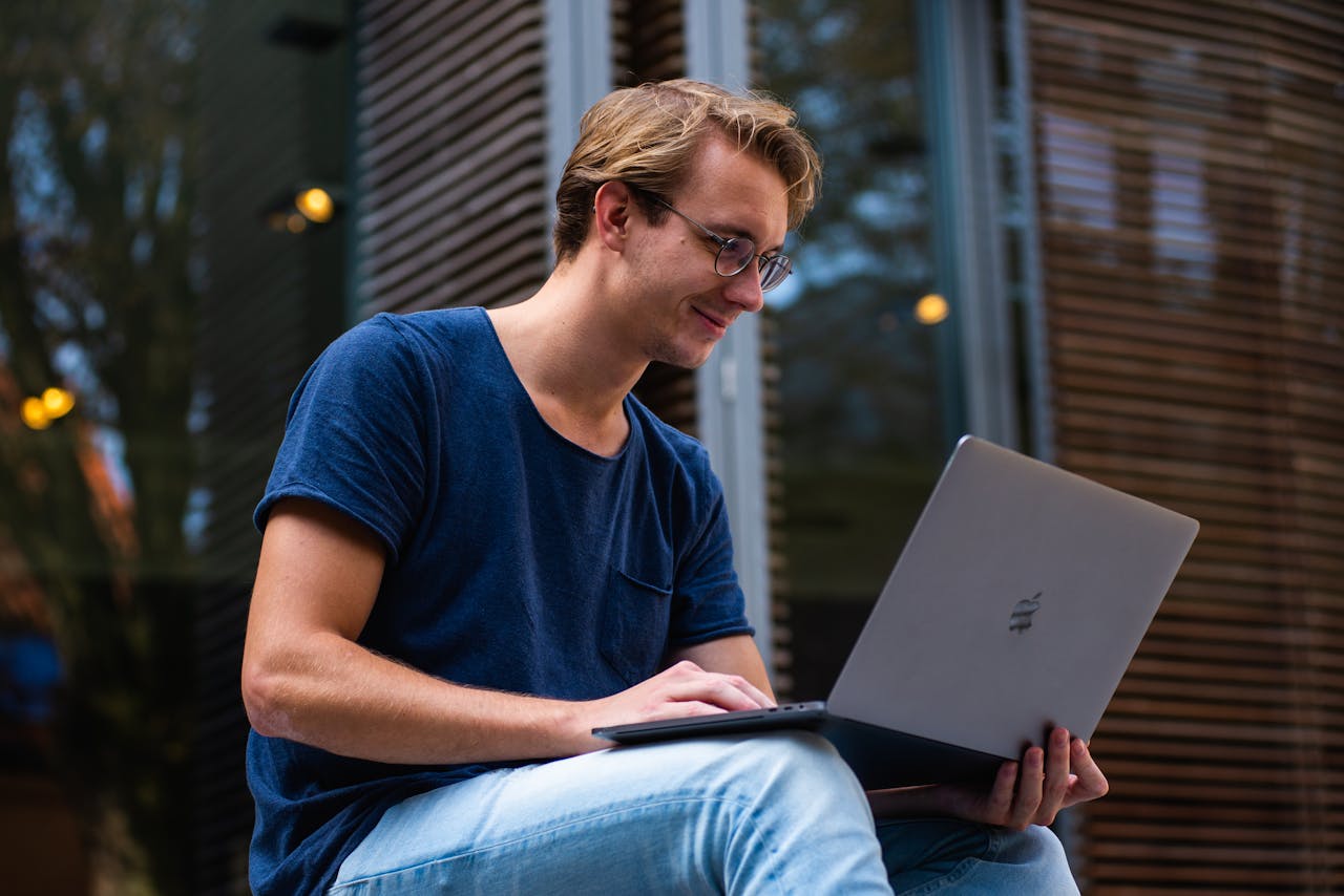 The Art of Drawing Readers In: Your attractive post title goes here A young man sitting outdoors in Leiden, Netherlands, working on a laptop.