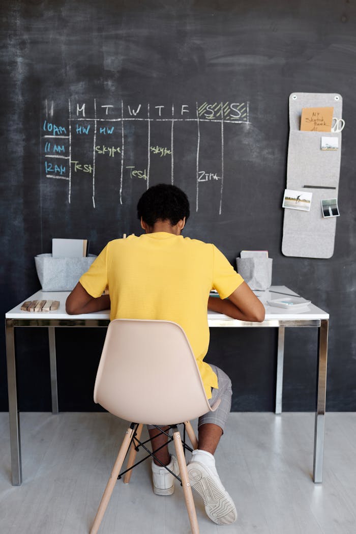 core-values A teenager focuses on studying at a desk, with a blackboard displaying a schedule in the background.