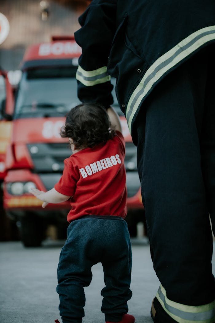 A firefighter guiding a child near a fire truck, showcasing safety and courage.