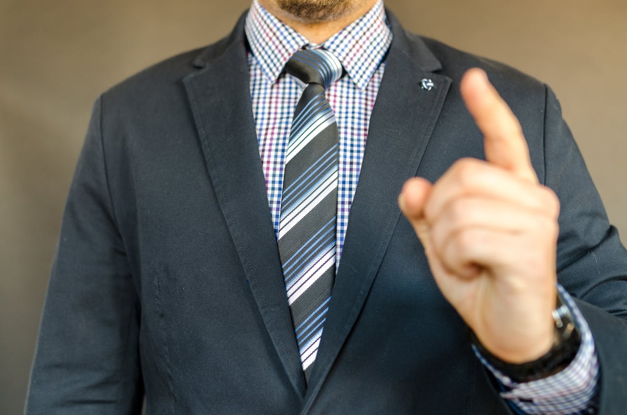 Close-up of a man in a suit making a gesture, symbolizing instruction or guidance.