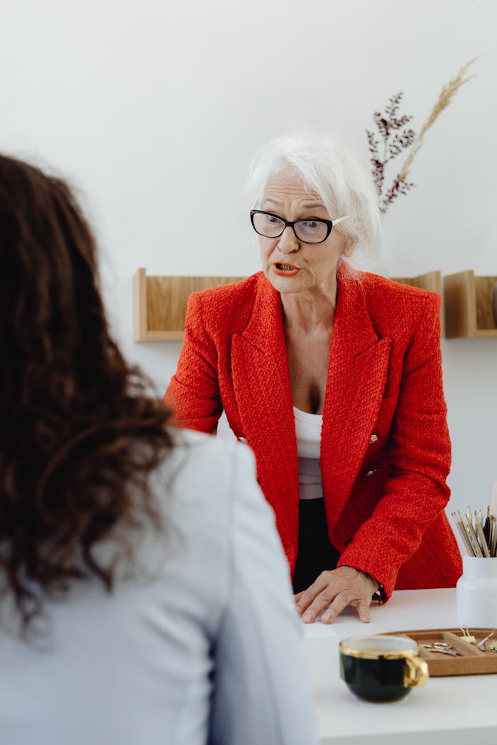 Senior businesswoman in a red blazer engaging in a professional meeting at the office.